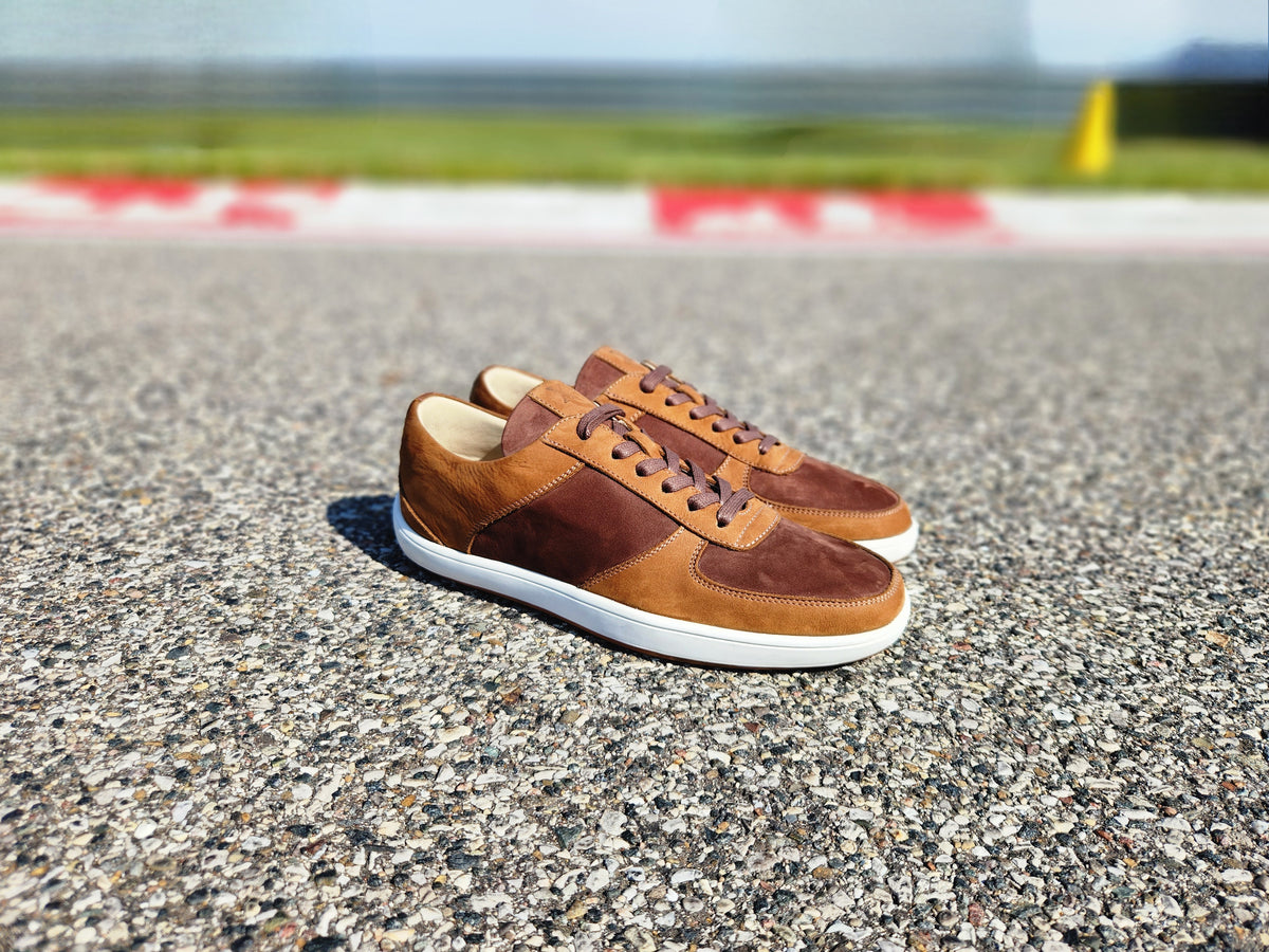 Pair of brown leather shoes on a road with a blurred background